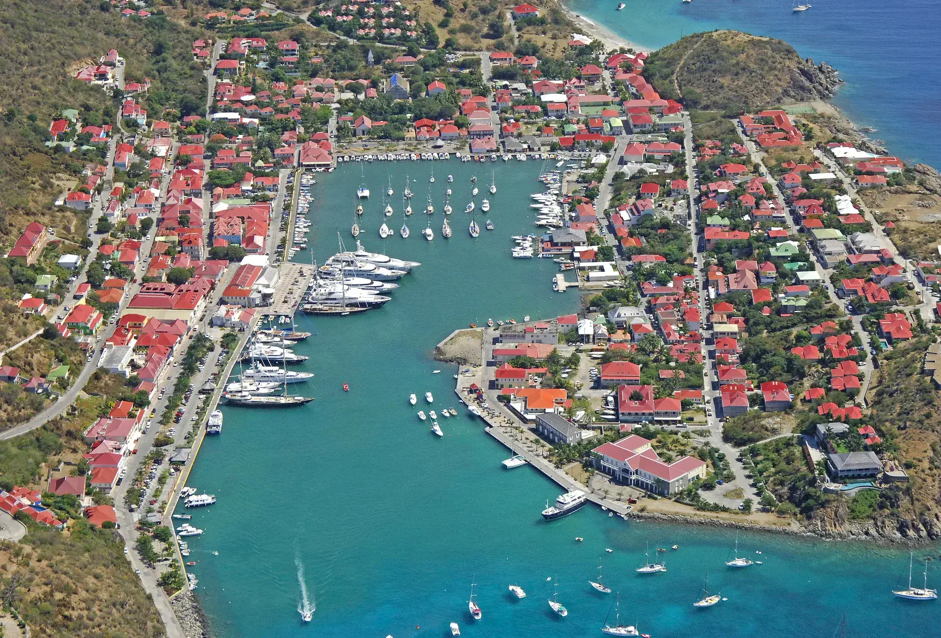 Vue aérienne de Gustavia et de sa ville portuaire aux toits rouges à Saint-Barth, des yachts remplissant le port qui porte le nom d’un roi suédois