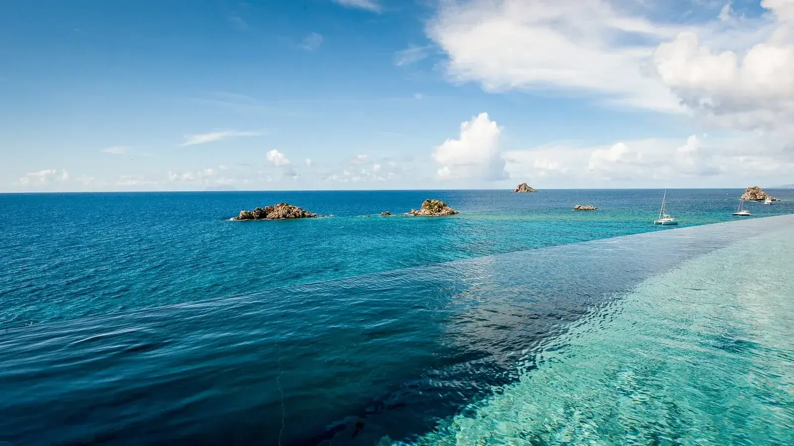 The edge of an infinity pool merging with the sea, islets on the horizon