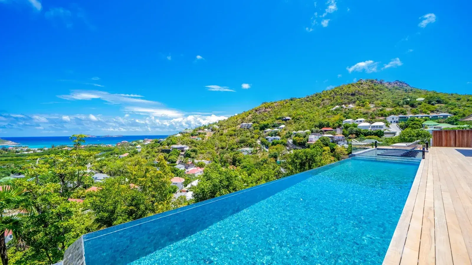 An infinity pool over the hills of St Jean, the bay in the distance