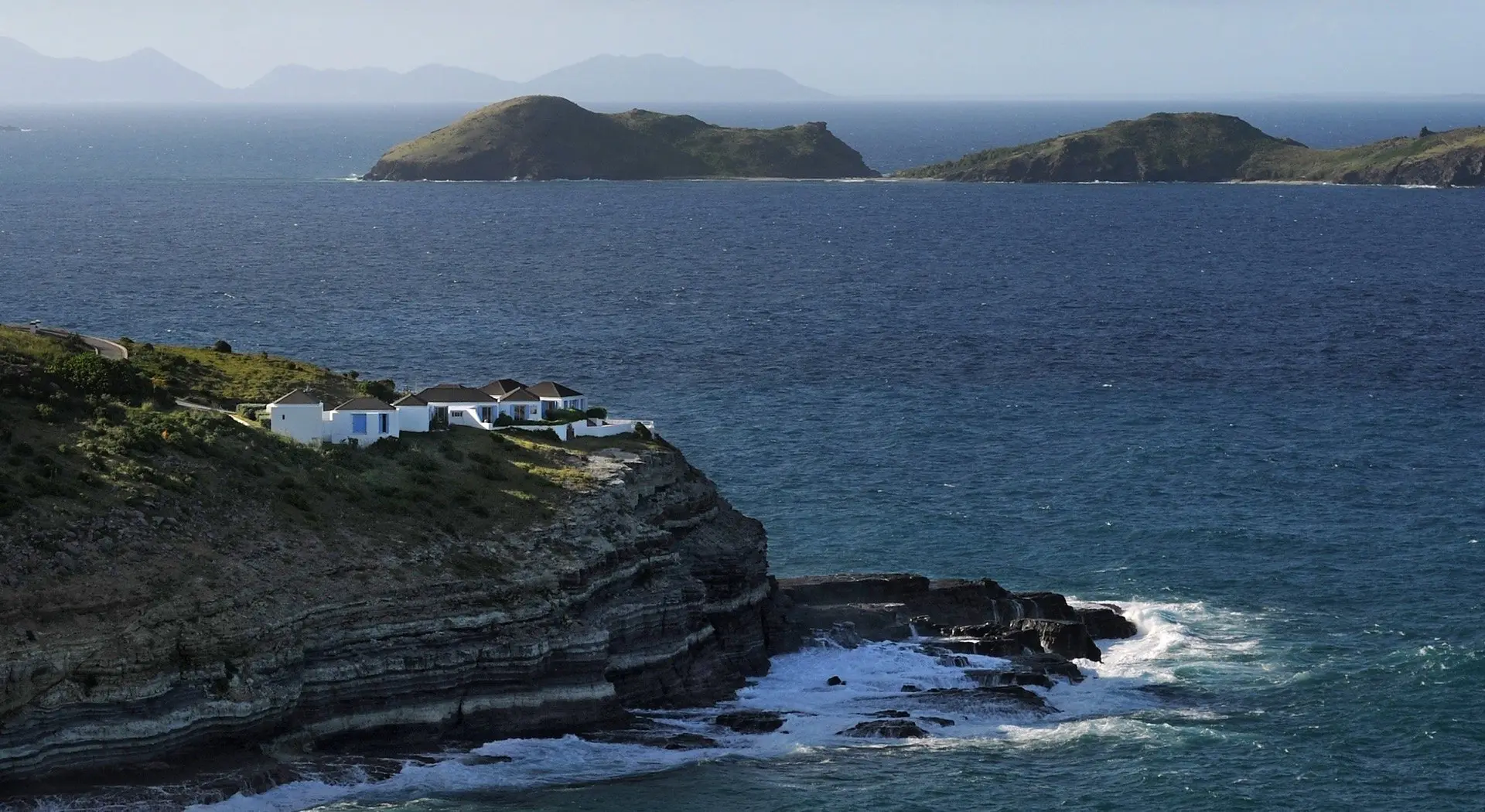 Waves breaking on a rocky stretch of coast, an islet offshore
