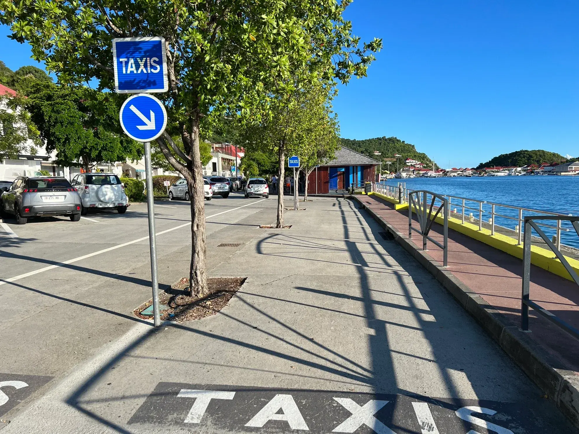 The taxi sign and rank on the waterfront in Gustavia, a car parked under the trees