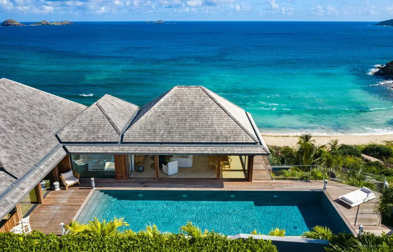 A villa and its pool right above the sea, islets on the horizon