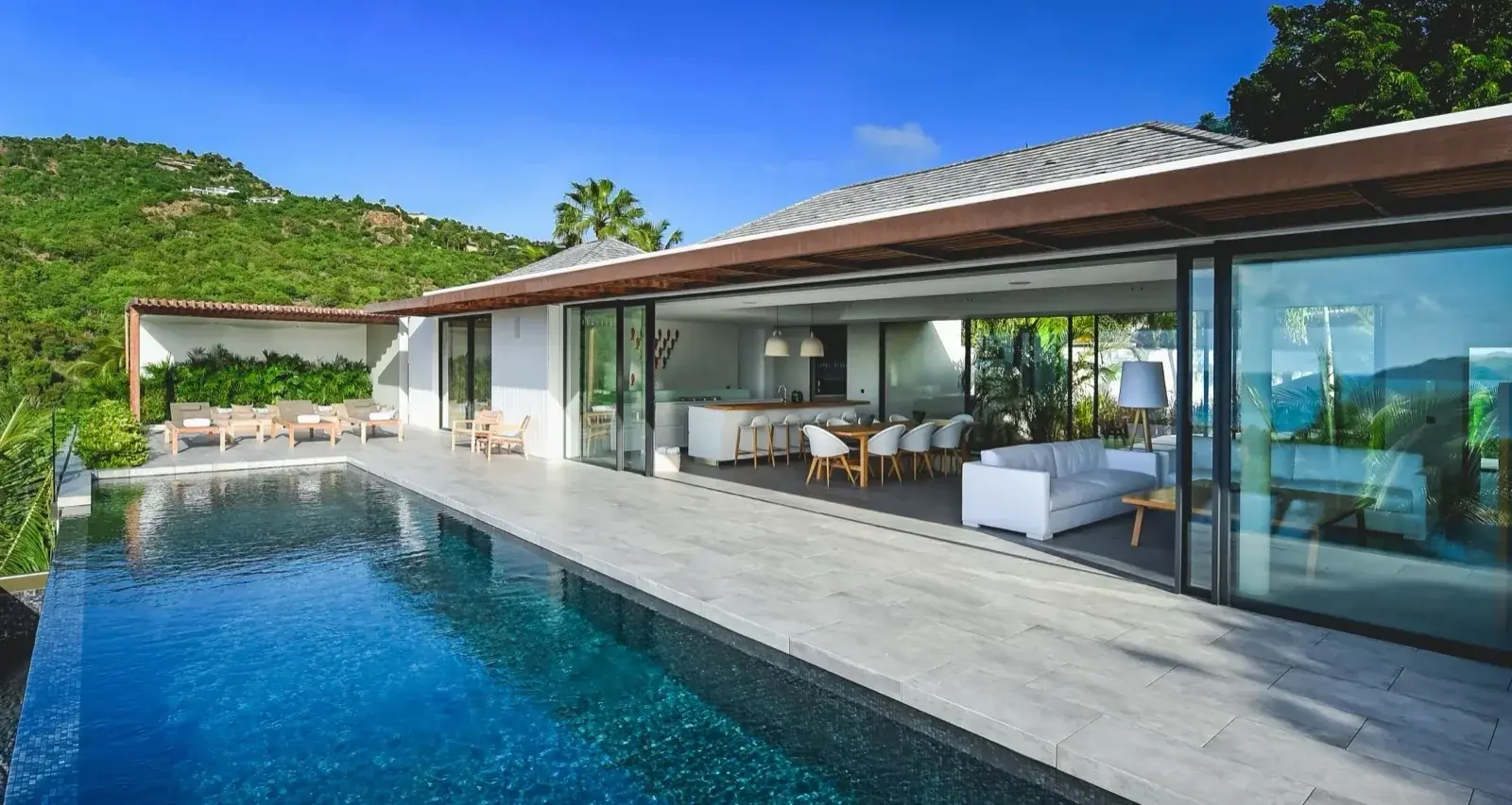 A modern villa opening onto its pool, the living room wide open